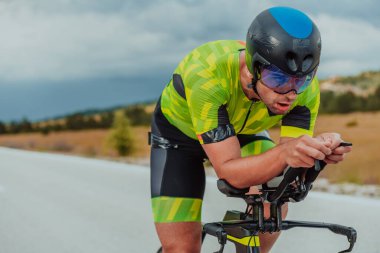 Full length portrait of an active triathlete in sportswear and with a protective helmet riding a bicycle. Selective focus.
