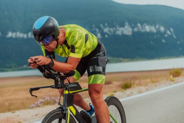 Full length portrait of an active triathlete in sportswear and with a protective helmet riding a bicycle. Selective focus.