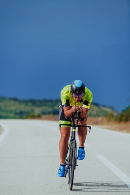 Full length portrait of an active triathlete in sportswear and with a protective helmet riding a bicycle. Selective focus.