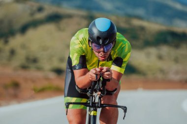 Full length portrait of an active triathlete in sportswear and with a protective helmet riding a bicycle. Selective focus.