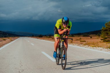 Full length portrait of an active triathlete in sportswear and with a protective helmet riding a bicycle. Selective focus.
