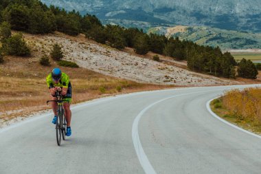 Full length portrait of an active triathlete in sportswear and with a protective helmet riding a bicycle. Selective focus.