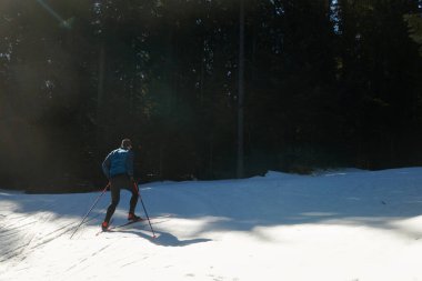 Nordic skiing or Cross-country skiing classic technique practiced by man in a beautiful panoramic trail at morning. Selective focus 