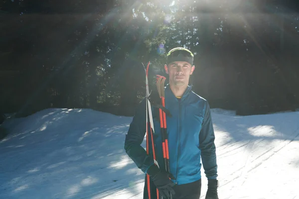 形象英俊的男性运动员 手拿越野滑雪板和护目镜 在雪地的森林里接受训练 健康的冬季生活方式概念 — 图库照片