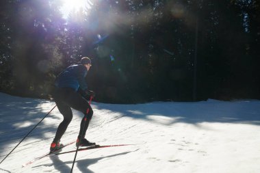 Nordic skiing or Cross-country skiing classic technique practiced by man in a beautiful panoramic trail at morning. Selective focus 