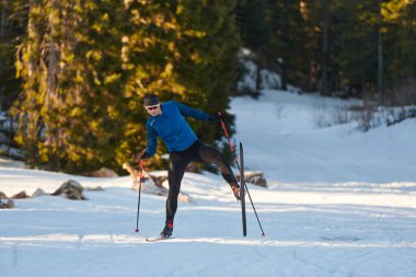 Nordic skiing or Cross-country skiing classic technique practiced by man in a beautiful panoramic trail at morning. Selective focus 