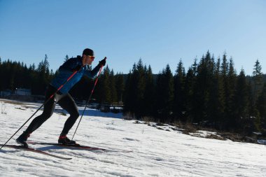 Nordic skiing or Cross-country skiing classic technique practiced by man in a beautiful panoramic trail at morning. Selective focus 