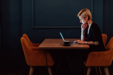 Businesswoman sitting in a cafe while focused on working on a laptop and participating in an online meetings. Selective focus