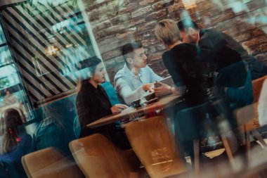 Happy businesspeople smiling cheerfully during a meeting in a coffee shop. Group of successful business professionals working as a team in a multicultural workplace. 