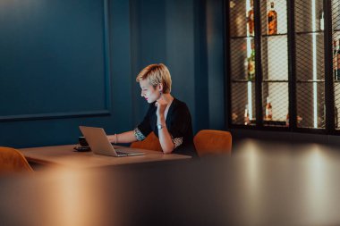 Businesswoman sitting in a cafe while focused on working on a laptop and participating in an online meetings. Selective focus