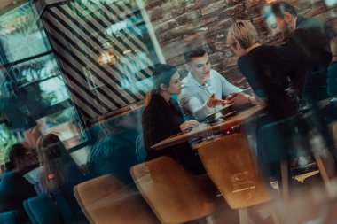 Happy businesspeople smiling cheerfully during a meeting in a coffee shop. Group of successful business professionals working as a team in a multicultural workplace. 
