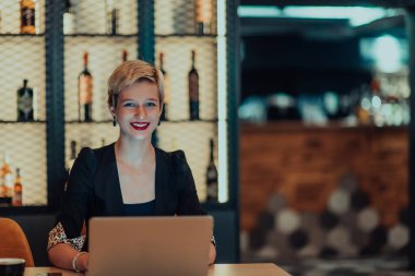 Businesswoman sitting in a cafe while focused on working on a laptop and participating in an online meetings. Selective focus