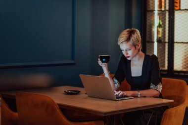 Businesswoman sitting in a cafe while focused on working on a laptop and participating in an online meetings. Selective focus