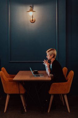 Businesswoman sitting in a cafe while focused on working on a laptop and participating in an online meetings. Selective focus