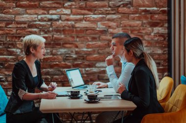 Happy businesspeople smiling cheerfully during a meeting in a coffee shop. Group of successful business professionals working as a team in a multicultural workplace. 
