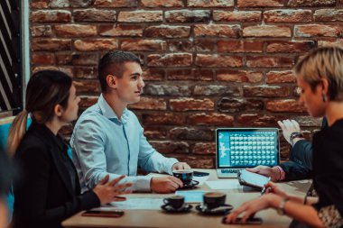 Happy businesspeople smiling cheerfully during a meeting in a coffee shop. Group of successful business professionals working as a team in a multicultural workplace. 