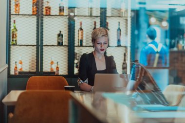 Businesswoman sitting in a cafe while focused on working on a laptop and participating in an online meetings. Selective focus