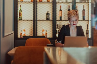 Businesswoman sitting in a cafe while focused on working on a laptop and participating in an online meetings. Selective focus
