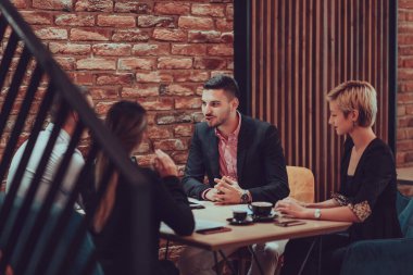 Happy businesspeople smiling cheerfully during a meeting in a coffee shop. Group of successful business professionals working as a team in a multicultural workplace. 