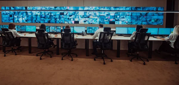 Group of Security data center operators working in a CCTV monitoring room looking on multiple monitors.Officers Monitoring Multiple Screens for Suspicious Activities.