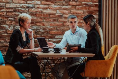 Happy businesspeople smiling cheerfully during a meeting in a coffee shop. Group of successful business professionals working as a team in a multicultural workplace. 