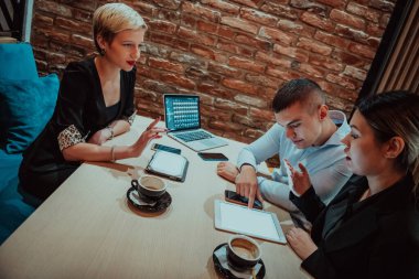 Happy businesspeople smiling cheerfully during a meeting in a coffee shop. Group of successful business professionals working as a team in a multicultural workplace. 