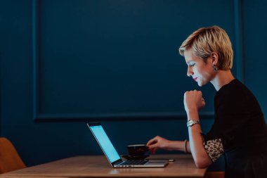 Businesswoman sitting in a cafe while focused on working on a laptop and participating in an online meetings. Selective focus