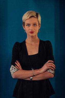 Blonde business woman, successful confidence with arms crossed on modern blue mat background. Selective focus. 