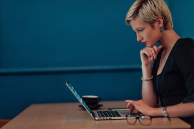 Businesswoman sitting in a cafe while focused on working on a laptop and participating in an online meetings. Selective focus