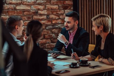 Happy businesspeople smiling cheerfully during a meeting in a coffee shop. Group of successful business professionals working as a team in a multicultural workplace. 