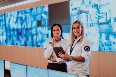 Group portrait of female security operator while working in a data system control room offices Technical Operator Working at workstation with multiple displays.