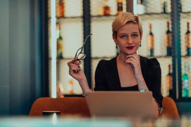 Businesswoman sitting in a cafe while focused on working on a laptop and participating in an online meetings. Selective focus