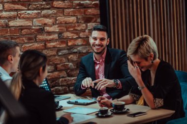 Happy businesspeople smiling cheerfully during a meeting in a coffee shop. Group of successful business professionals working as a team in a multicultural workplace. 