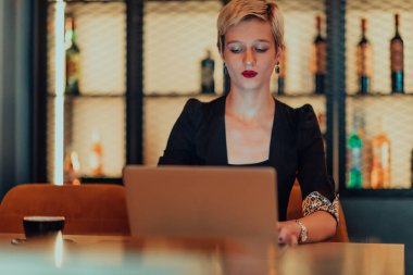 Businesswoman sitting in a cafe while focused on working on a laptop and participating in an online meetings. Selective focus