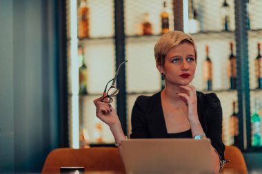 Businesswoman sitting in a cafe while focused on working on a laptop and participating in an online meetings. Selective focus