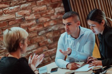 Happy businesspeople smiling cheerfully during a meeting in a coffee shop. Group of successful business professionals working as a team in a multicultural workplace. 
