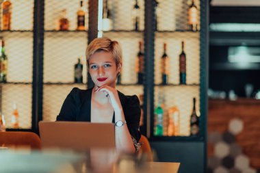 Businesswoman sitting in a cafe while focused on working on a laptop and participating in an online meetings. Selective focus