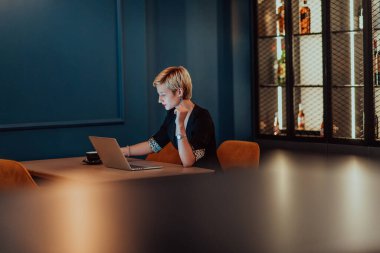 Businesswoman sitting in a cafe while focused on working on a laptop and participating in an online meetings. Selective focus
