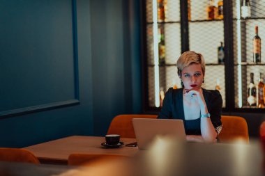 Businesswoman sitting in a cafe while focused on working on a laptop and participating in an online meetings. Selective focus