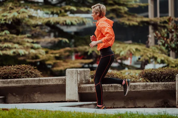 stock image  A blonde in a sports outfit is running around the city in an urban environment. The hot blonde maintains a healthy lifestyle