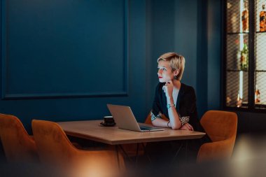 Businesswoman sitting in a cafe while focused on working on a laptop and participating in an online meetings. Selective focus