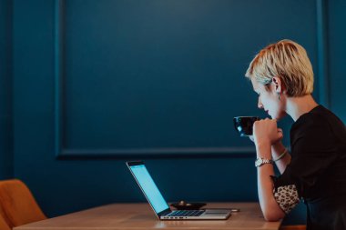 Businesswoman sitting in a cafe while focused on working on a laptop and participating in an online meetings. Selective focus