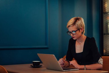Businesswoman sitting in a cafe while focused on working on a laptop and participating in an online meetings. Selective focus