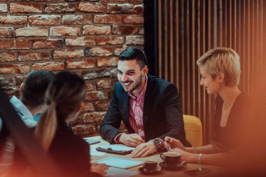 Happy businesspeople smiling cheerfully during a meeting in a coffee shop. Group of successful business professionals working as a team in a multicultural workplace. 