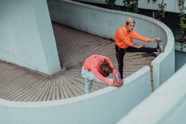 Two women warming up together and preparing for a morning run in an urban environment. Selective focus . 
