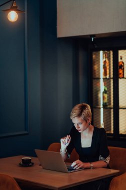 Businesswoman sitting in a cafe while focused on working on a laptop and participating in an online meetings. Selective focus
