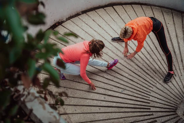二人の女性が一緒に温暖化し 都市環境での朝の実行のために準備 選択的焦点 — ストック写真