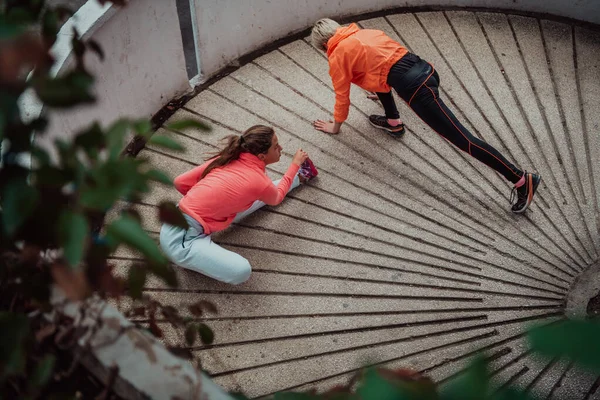 二人の女性が一緒に温暖化し 都市環境での朝の実行のために準備 選択的焦点 — ストック写真