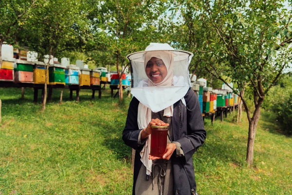彼女の手に蜂蜜の瓶を保持する蜂蜜農場の養蜂部門のイスラム教徒アフリカ系アメリカ人女性の肖像画 — ストック写真