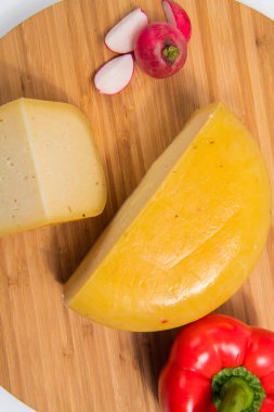 Bosnian traditional cheese served on a wooden container with peppers, parade and onions isolated on a white background.
